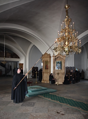 Церковник зажигает паникадило