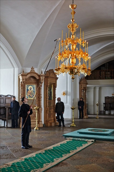 Церковник зажигает паникадило