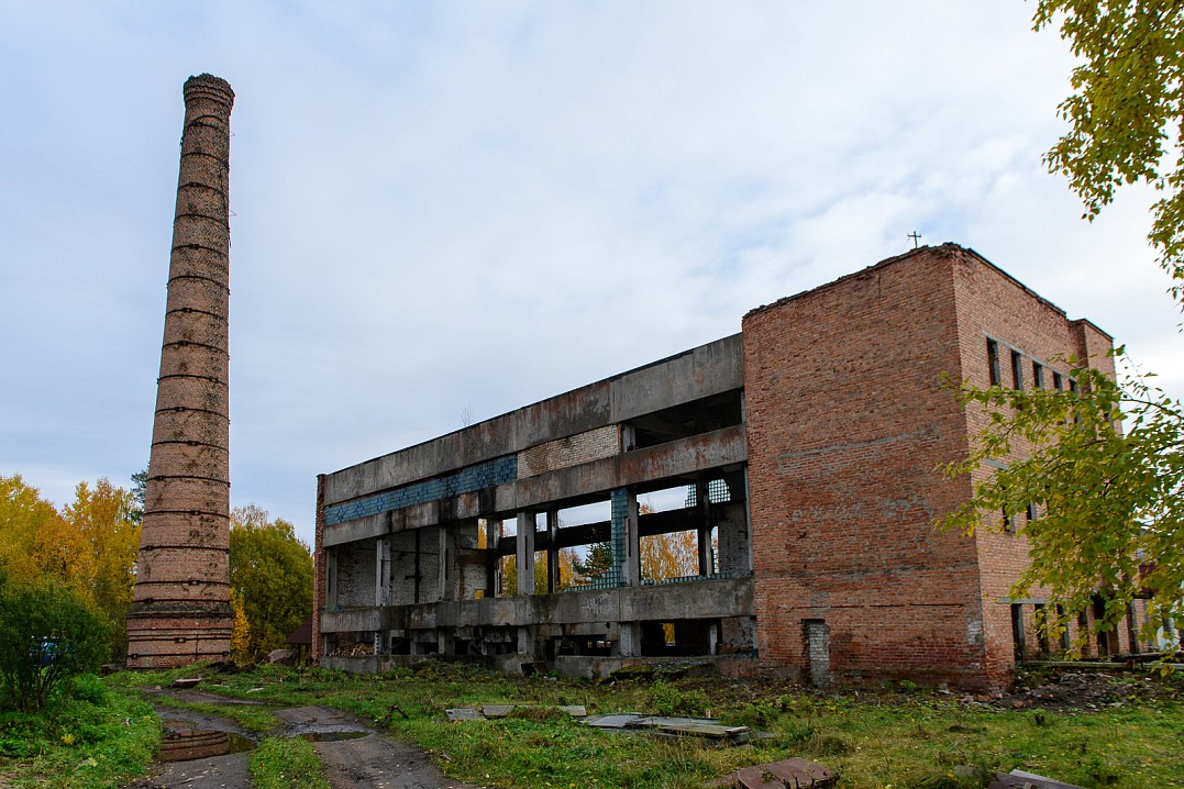 Рядом с храмом стоят труба бывшей котельной и полуразрушенное здание.
